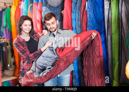 Couple heureux d'examiner diverses sacs de couchage au magasin d'équipement de sport Banque D'Images