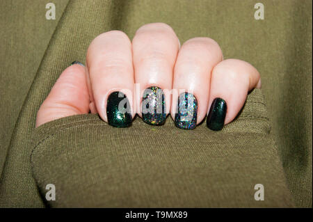 Women's Hands - belle manucure, pose de vernis sur les ongles de différentes nuances de vert, avec une légère brillance et grande brillance Banque D'Images