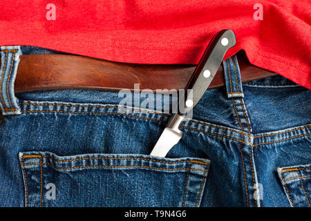Crime de couteau. Un couteau dans la poche arrière de jeans en denim. Banque D'Images