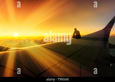 Le voyage d'aventure Photo conceptuelle de Silhouette de l'homme assis sur l'aile d'avion regarder magnifique coucher de Destination Monde Banque D'Images