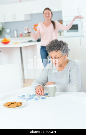 Parler à grand-mère alors qu'elle est en train de faire puzzle Banque D'Images