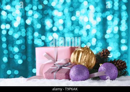 Cadeaux de Noël et des décorations sur la neige contre Lumières floues Banque D'Images