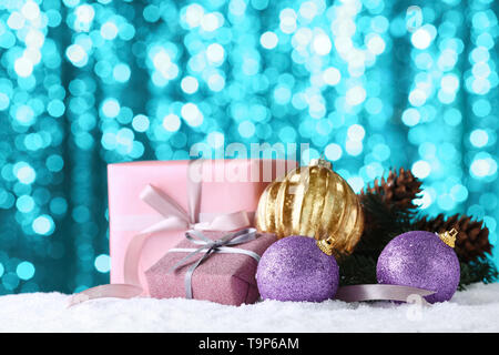 Cadeaux de Noël et des décorations sur la neige contre Lumières floues Banque D'Images