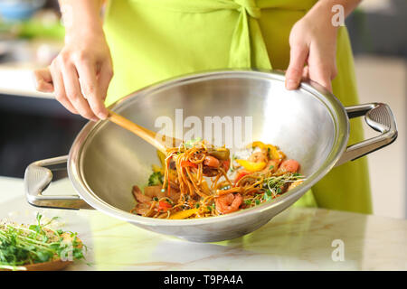 Woman cooking délicieux nouilles chinoises au wok Banque D'Images