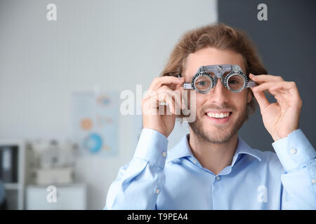 Jeune homme avec montures d'essai clinique en ophtalmologie Banque D'Images