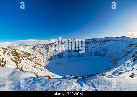 Vue panoramique sur le volcan Kerid avec de la neige et de la glace dans le lac de cratère volcanique en hiver sous un ciel bleu clair. situé dans le domaine Grímsnes Banque D'Images