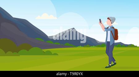 L'homme en tenant l'appareil photo de votre smartphone selfies photo de personnage masculin occasionnels dans la région de hat avec sac à dos montagne fond paysage pleine longueur à plat Illustration de Vecteur