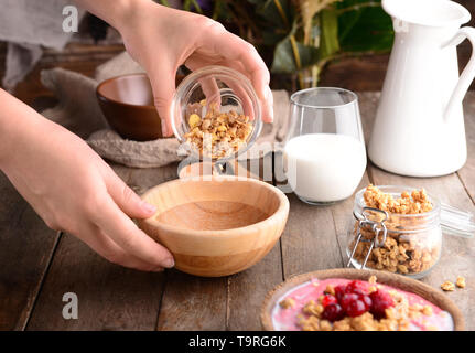 Femme préparant de délicieux muesli in kitchen Banque D'Images