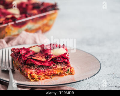 Paniers de légumes lasagne sur plaque rose Arc-en-ciel. Idées et recettes pour le déjeuner ou dîner végétarien sain. Lasagnes à la betterave rouge, potiron, champignons, épinards, ricotta, de la mozzarella. L'espace de copie pour le texte. Banque D'Images