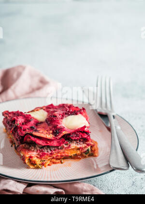 Paniers de légumes lasagne sur plaque rose Arc-en-ciel. Idées et recettes pour le déjeuner ou dîner végétarien sain. Lasagnes à la betterave rouge, potiron, champignons, épinards, ricotta, de la mozzarella. L'espace de copie pour le texte. Banque D'Images