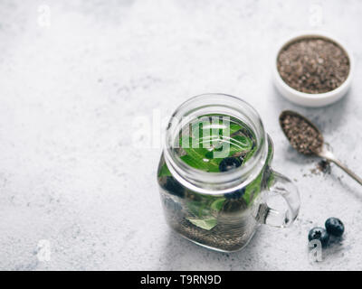 Vue du dessus de l'eau dans la région de chia pot Mason de menthe et de bleuet sur fond de ciment gris. Chia infusé avec de l'eau detox de baies. L'espace de copie pour le texte. La saine alimentation, boissons, alimentation, concept detox Banque D'Images