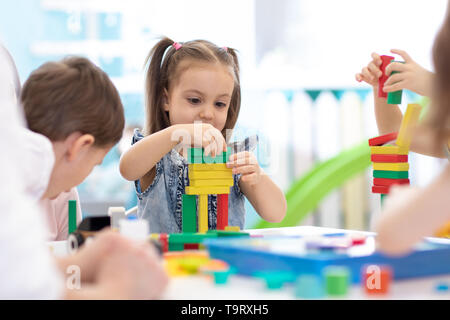 Peu d'enfants à construire des jouets en bois à la maison ou à la garderie. Les enfants jouent avec la couleur émotionnelle des blocs. Jouets éducatifs pour les enfants d'âge préscolaire et de la maternelle. Banque D'Images