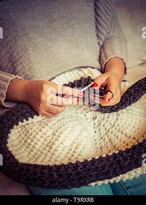 Girl making a puff crochet avec de la laine blanche et grise et les ongles peints en rouge close up photographie, artisanat Banque D'Images