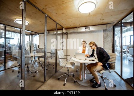 Homme et femme d'affaires travaillant dans la salle de réunion, une large vue sur l'intérieur de la pièce avec cloisons transparentes Banque D'Images