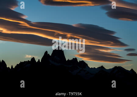 Nuages lenticulaires colorés sur le massif du Fitz Roy et le Cerro Torre en silhouette au coucher du soleil dans le Parc National Los Glaciares, près d'El Chalten, Argentine. Banque D'Images