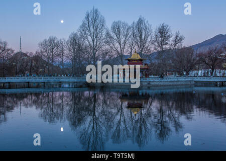 L'aube d'une image de la lune au cours d'une petite pagode au bord du lac dans la place du Potala à Lhassa, au Tibet. Banque D'Images