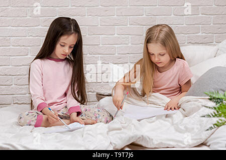 Photos de dessin pour les enfants tout en étant allongé sur le lit. soirée pyjama et l'amitié. Banque D'Images