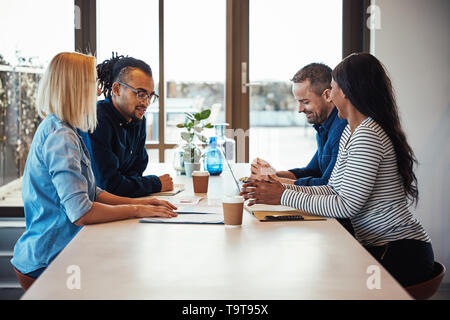 Smiling group de collègues discuter d'affaires ensemble au cours d'une réunion autour d'une table Banque D'Images