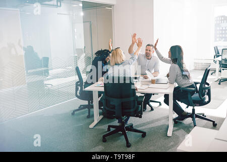 Groupe de travail diversifié sourire collègues assis autour d'une table de bureau et de l'autre, on subit donc élevé au cours d'une réunion Banque D'Images