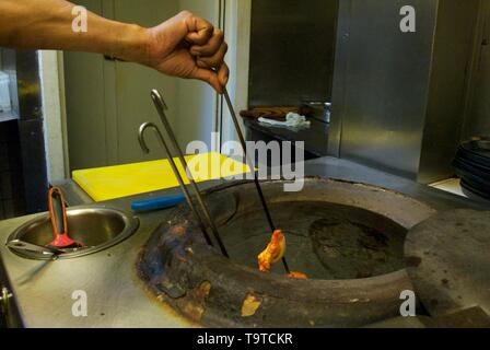 Un chef cuisiner dans un four tandoori brochettes dans une cuisine indienne Banque D'Images