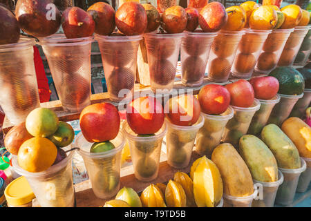 Fruits dans des gobelets en plastique, prêtes à être transformées en fruits frais au marché de Luang Prabang, la variété de fruits mûrs sur le comptoir d'Asie. Banque D'Images