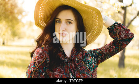 Portrait de l'été, belle jeune femme portant chapeau de paille à l'heure du coucher du soleil sur le jardin Banque D'Images