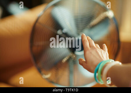 À main de femme qui s'étend au sol électriques ventilateur sur pied dans la maison moderne en chaude journée d'été ensoleillée. Banque D'Images