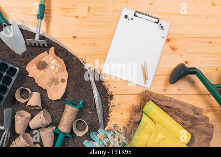 La production d'aliments biologiques peu coûteux et équipements de jardinage, vue du dessus d'outils et de semences sur table en bois dans jardin avec quelques pièces en euro concept de l Banque D'Images