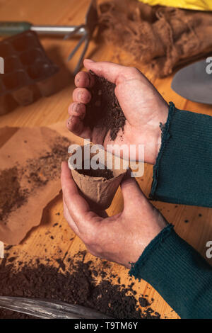 Remplissage jardinier biodegradable SOIL conteneur pot prêtes à semer et planter des graines dans la production alimentaire biologique garden, Close up of female hands Banque D'Images