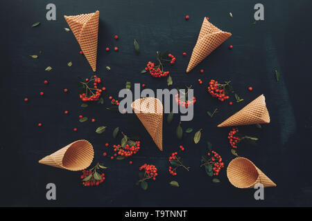 Waffle ice cream cone télévision jeter dessus noir foncé sur fond de bois décoré de petits fruits sauvages arrangement Banque D'Images