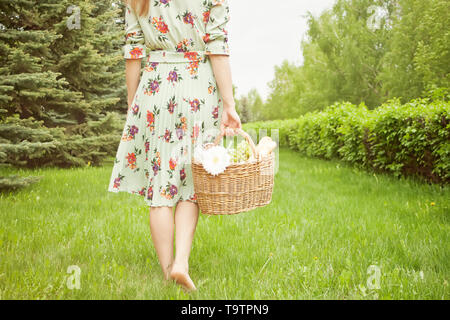 Femme dans une robe sur l'aire de pique-nique panier pique-nique tient dans une main. Banque D'Images