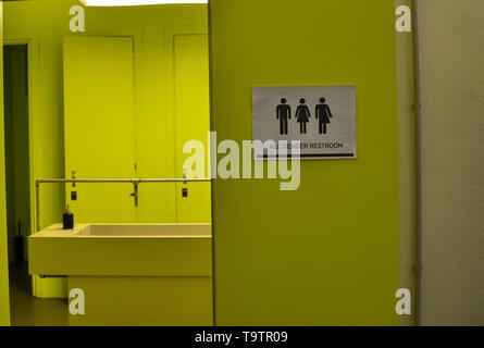 La signalisation des toilettes toutes sortes à côté d'une porte de la salle de bains en vert acide avec des icônes de l'homme, de la femme, les transgenres. Icônes noires sur un fond blanc Banque D'Images