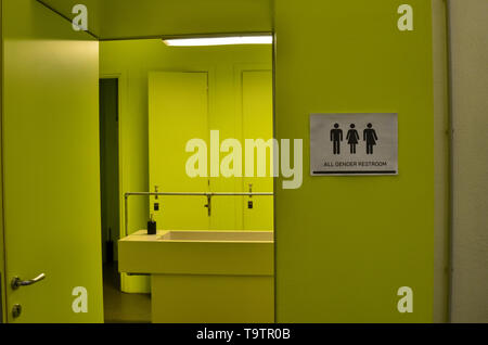 La signalisation des toilettes toutes sortes à côté d'une porte de la salle de bains en vert acide avec des icônes de l'homme, de la femme, les transgenres. Icônes noires sur un fond blanc Banque D'Images