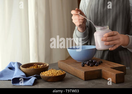 Femme préparant de délicieux muesli in kitchen Banque D'Images