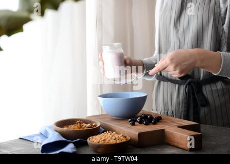 Femme préparant de délicieux muesli in kitchen Banque D'Images