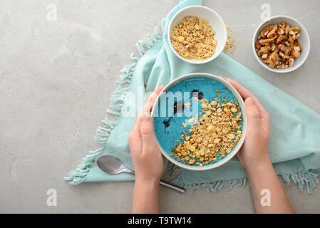 Femmes avec de savoureux muesli dans un bol sur fond gris Banque D'Images