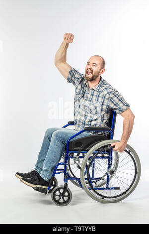 Homme handicapé sur fauteuil roulant avec bras levé en signe de victoire. Concept de défi et de positivité. Banque D'Images