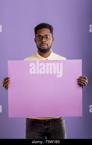 Portrait of young african american businessman confiant dans les verres montrant présentation holding blank paper plaque pour votre message texte publicitaire Banque D'Images