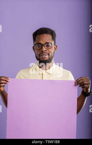 Portrait of young african american businessman confiant dans les verres montrant présentation holding blank paper plaque pour votre message texte publicitaire Banque D'Images