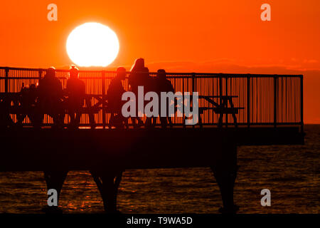 Pays de Galles Aberystwyth UK, lundi 20 mai 2019 UK Weather : les gens sur le quai en prenant un verre et la vue du glorieux coucher du soleil doré sur la baie de Cardigan, à la fin d'une journée de soleil du printemps chaud à Aberystwyth au Pays de Galles. La météo est très bien pour les jours à venir , avec des périodes de soleil crédit photo : Keith Morris / Alamy Live News Banque D'Images