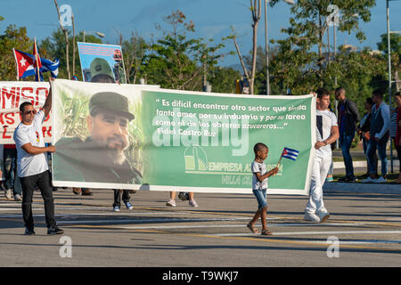 Santa Clara, Cuba le 1 mai 2019 : Groupe de personnes marchant avec des affiches et des drapeaux, un garçon noir avec un drapeau cubain Banque D'Images