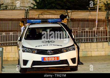 Jérusalem, Israël - 17 août 2016 : Young man leaning on orthodoxe juif voiture de police à l'extérieur de la porte du fumier dans la vieille ville de Jérusalem, Israël Banque D'Images