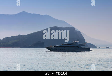 Silhouette d'un bateau en mer sur l'arrière-plan du Mont St Nicholas à Budva dans la brume du matin Banque D'Images