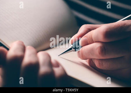 Gaucher woman writing journal, Close up of hands avec bloc-notes et crayon Banque D'Images