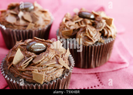 Cupcakes au beurre de cacao brun et crème de chocolat sur une nappe rose, gros plan, choisis focus, réduire la profondeur de champ Banque D'Images
