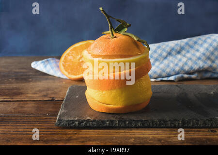 Les citrons et les oranges en tranches, empilés sur une table d'ardoise sur une vieille table en bois Banque D'Images