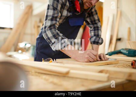 Mid section portrait de charpentier bois marquage méconnaissable en travaillant en menuiserie éclairée par la lumière du soleil, copy space Banque D'Images