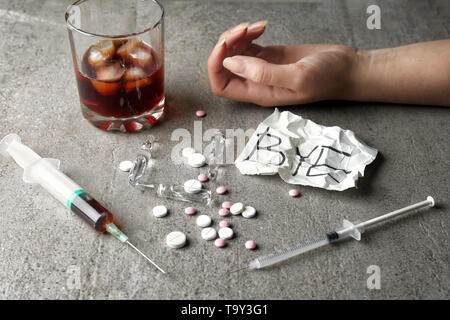 La femelle, seringue, pilules et verre d'alcool sur le tableau gris. Notion de suicide Banque D'Images