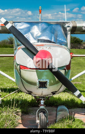 Vieux rouge et blanc l'hélice du moteur unique avion, vue avant, stationné sur le terrain d'herbe journée ensoleillée. Banque D'Images