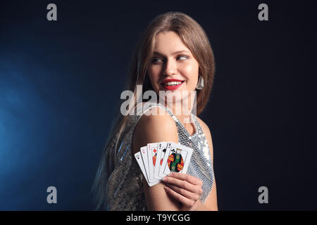 Belle jeune femme avec cartes sur fond sombre Banque D'Images